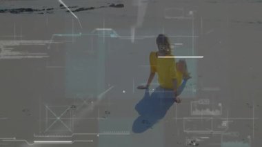 Yetişkin bir kadın kumlu sahilde oturmuş teknik veri panellerini ve çizelgeleri aktifleştiriyor. Gelecekçi, yenilikçi, teknoloji, açık hava, sükunet, minimalist, dijital