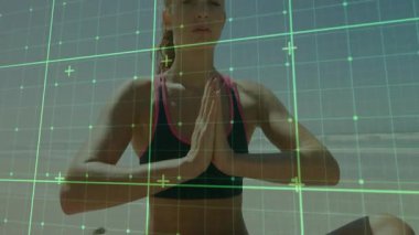 Sahilde oturan, nefes alan, yeşil ızgara altında spor yapmak için kollarını kaldırıp dua eden bir kadın. Meditasyon, huzur, denge, sağIık, farkındalık, sükunet, tefekkür