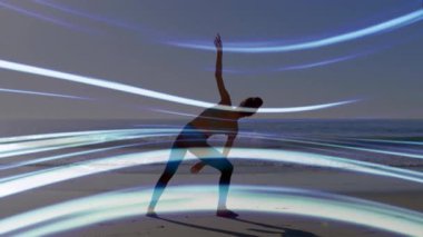 Sahilde güneş doğarken poz veren kadın ışık dalgalarını aktifleştiriyor ve sağlık için siluet dokuyor. Siluet, ahenk, meditasyon, dinginlik, estetik, hareket, enerji