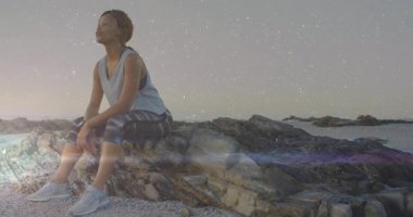 Fitness akıllı seğirme uyarısı duruş değişikliğine ve kıyıda beşikteki bir kadının başını eğmesine neden oluyor. Yalnızlık, yansıma, farkındalık, esneklik, doğa, huzur, tefekkür