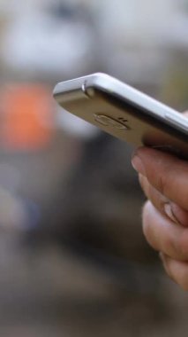 Telefonuna güvenlik yeleği giyen bir işçinin dijital bileşimi. Yanında bir mesaj baloncuğunun dijital animasyonu ve takip eden simgesi var.