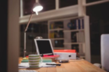 Tahta masadaki lambaya göre dijital tabletin ve dosyaların odaksız görüntüsü