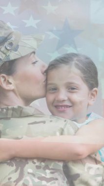 Amerikan bayrağının üzerinde gülümseyen kızını kucaklayan kadın askerin animasyonu. Asker, dijital olarak üretilen aile imajına geri dönüyor..