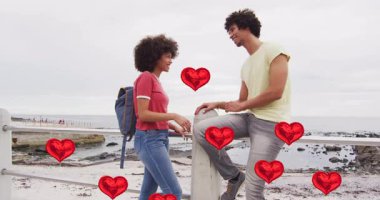 Kıyıdaki korkuluklarda karşılıklı selamlaşan ve flört uygulaması pazarlaması için kalplerini sallamaya başlayan bir çift. Romantizm, şefkat, bağlantı, açık hava, anlamlı, arkadaşlık, duygusal