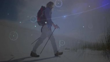 Erkek yürüyüşçü direklere basıyor, kum tepecikleri boyunca yürüyor ve manzara üzerindeki teknolojik HUD grafiklerini ortaya çıkarıyor. Macera, keşif, fütürizm, teknoloji, açık hava, vahşi doğa, yenilik