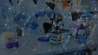 Araştırma ekibi laboratuvarda toplanıp ağ örtüsü ile mikroskop altında kaymayı hazırlıyor ve analiz ediyor. Bilim, işbirliği, yenilik, teknoloji, sağlık, araştırma, modern