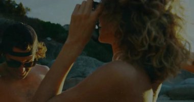 Üç arkadaş eğlence için plaj müziğine cevap veriyor, kırmızı bardaklardan içiyor ve tezahürat yapıyorlar. Eğlence, kutlama, yoldaşlık, eğlence, açık hava, hayat dolu, gençlik dolu.