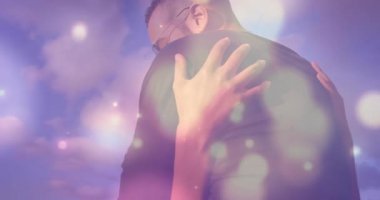 Pastel gökyüzünün altında kucaklaşan çift sağlıklı olmak için ellerini omuzlarına koyuyor. Romantizm, samimiyet, şefkat, açık hava, pastel, dinginlik, bağlantı