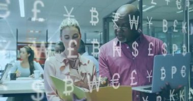 Kadın sarı klasörü çeviriyor, kıdemli adam dizüstü bilgisayarında yüzen para sembolleri taşıyor. İşbirliği, takım çalışması, veri analizi, kurumsal çevre, profesyonel, finans, modern ofis