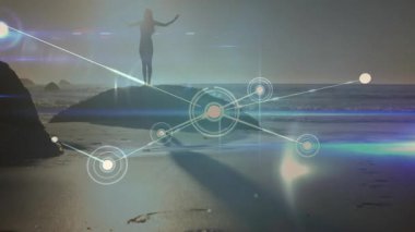 Kaya gibi yükselen kolların üzerinde duran bir kadın parıldayan teknoloji veri ağını başlatıyor ve kıyı şeridi boyunca genişliyor. Siluet, bağlantı, dijital, gün batımı, dinginlik, yenilik, manzara
