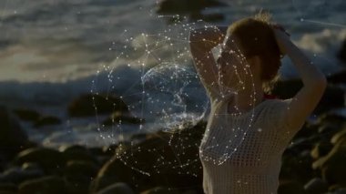 Kayalık sahilde saç toplayan bir kadın, dijital küreyi çağıran, teknolojide parıldayan bir ağ. Fütürist, soyut, minimalist, enerjik, bağlantı, yenilik, huzur