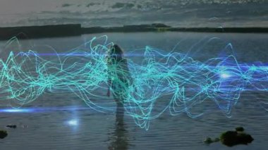 Bel yüksekliğindeki suya dalan bir kadın teknolojik gösteri için gövde etrafında canlanan deniz mavisi dalga formunu başlatıyor. Fütürist, dinginlik, teknoloji, dijital, su, soyut, yenilik