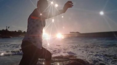 Çarpışan sörfte kayaya doğru koşan kadın günbatımına doğru kollarını dengede tutan spor ağı örtüsü için koşuyor. Macera, doğa, motivasyon, canlılık, dinginlik, dijital alarm, refah