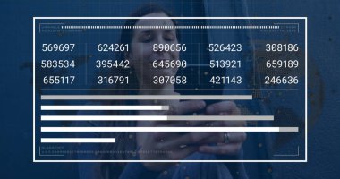 Holding smartphone and viewing digital data panel overlay against blue wall in denim jacket. Technology, analytics, data, urban, modern, business, communication