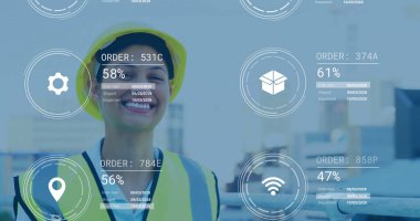 Female worker monitoring orders using digital UI overlays in logistics hall, with hard hat and vest. Industrial, logistics, technology, safety, automation, operational, warehouse