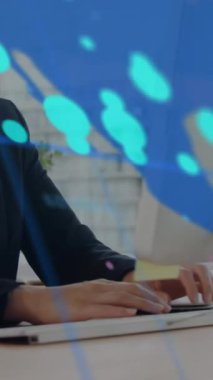 Bir iş kadını ofiste bir bilgisayar üzerinde çalışıyor. Veri, arka planda bir dünya haritasıyla işleniyor. Bu video küresel veri işleme, grafikler ve dijital arayüzler kavramını gösterir.