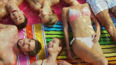 Arkadaşlar plaj havlusunda sohbet etmeye başlıyor. Rahatlatıcı yaşam tarzı için jest yapıyor ve gülüyorlar. Gündelik, açık hava, hareketli, boş zaman, yoldaşlık, yaz, sosyal