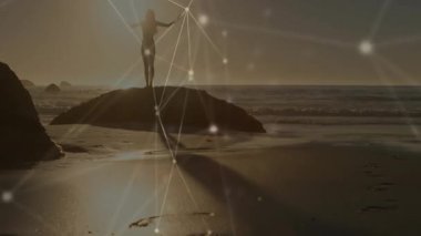 Güneşe batan ufuk, kıyıdaki kaya kolları dışa doğru kayan kadının etrafında teknolojiyi başlatıyor. Siluet, okyanus, günbatımı, maneviyat, bağlantı, sükunet