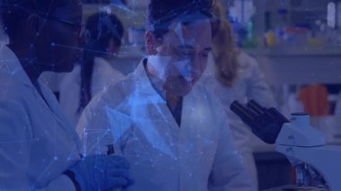 Laboratuvar bilim adamı, mikroskobu inceleyen ve veri kaydeden önde gelen erkek araştırmacılardan örnek hazırlıyor. Araştırma, işbirliği, laboratuvar, yenilik, kesinlik, kimya, keşif