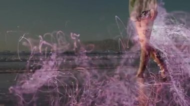 Alacakaranlık plajında manken yürüyüşü mor ışık yollarının kıvılcımları yukarı doğru kıvılcımlanması teknoloji gösterisi için vücudu sarmalar. Ateş, mistik, ruhani, aydınlatma, enerji, sükunet, zarafet