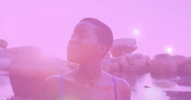 Model kare dışı hareketler ve dönen kafa modayla kayalık suda güneş ışığıyla çekiliyor. Sahil, manzara, gün batımı, kadınlık, dinginlik, doğa, macera