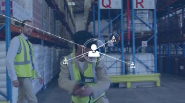 Depo teknisyeni VR kontrolörünü alıyor ve ağ simgelerini genişleterek rafların üzerindeki bağlantıları haritalıyor. Fütüristik, dijital, yenilik, endüstriyel, teknoloji, işbirliği, görselleştirme