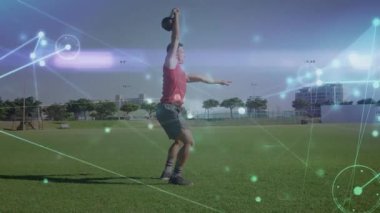 Antrenör topuklu ayakkabı kullanıyor ve ağırlık çalışması için çim tarlasında sallanan bir çaydanlık. Spor, güç, atletizm, açık hava, eğitim, dinamik, dayanıklılık