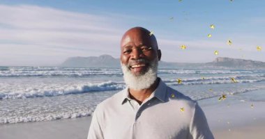 Sahilde duran kıdemli bir adam, sağ kahkahadan kayan altın yıldız grafiklerine tepki veriyor. Dinginlik, kutlama, pozitiflik, rahatlık, ilham verici, sakin, enerjik.