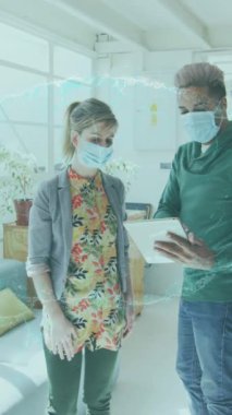 Animation of spinning human brain over businesswomen wearing face masks. global networks, business and connections during covid 19 pandemic concept digitally generated video.