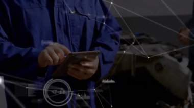 Teknisyen tıklama tableti ve iş arkadaşı motoru incelerken garajı birbirine bağlayan verileri gösteriyor. Teknoloji, bakım, bağlantı, mühendislik, dijital, endüstriyel, işbirliği