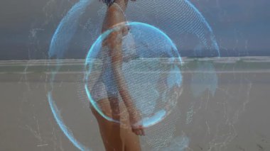 Kumsalda yürüyen bir kadın küresel teknoloji bağlantısını gösteren dijital dünyayı aktifleştiriyor. Teknoloji, bağlantı, küreselleşme, yenilik, dijital, ağ, ufuk