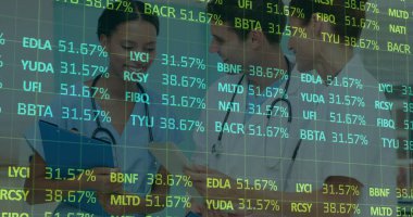 Reviewing notes, digital grid tickers, three medical experts in scrubs, coats consulting in hallway. Medical, collaboration, healthcare, digital, analysis, teamwork, professionalism