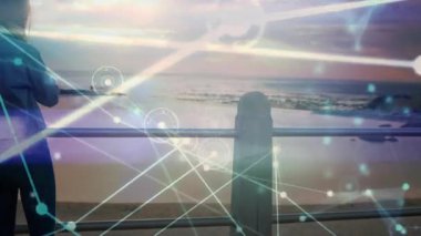 Sürüklenen teknolojik düğümlerin arasında gelen çağrılara cevap vermek için korkuluklara yaslanmış akıllı telefondan kulağa doğru uzanan bir kadın. Sahil şeridi, bağlantı, sükunet, teknoloji, dinlenme, dijital, yaşam tarzı