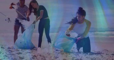 Üç gönüllü kıyıya mavi çanta yayıyor ve plaj temizliği için plastik topluyor. Gönüllüler, aktivizm, çevre, koruma, takım çalışması, açık hava, sürdürülebilir