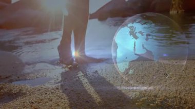 Kıyı şeridinde yalınayak duran, ağırlık değiştiren, teknolojiyi gösteren ışık ışınları yollayan biri. Navigasyon, yenilik, bağlantı, dinginlik, fütüristik, doğal, keşif