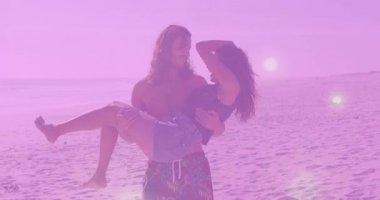 Kadın kaldıran gömleksiz bir adam ve güneş batan plajda yürüyen mercekli seyahat pazarlamacısı. Romantizm, macera, boş zaman, açık hava, sıcak, manzaralı, bağlantı