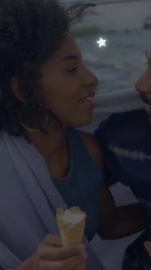 Sahilde birbirini kucaklayan Afro-Amerikan çifti üzerine parlayan yıldız ikonlarının animasyonu. Aşk ve ilişki kavramı