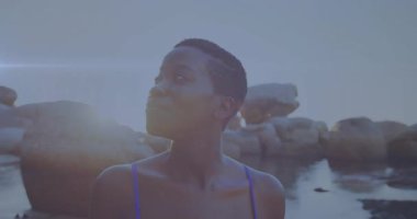 Kayalık kıyı şeridinde duran bir kadın seyahat görüntülerini çekerken gündoğumu lenslerini takip ediyor. Kıyı, sükunet, keşif, doğa, macera, sükunet, manzara