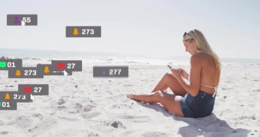 Sahildeki sosyal medya simgelerinde telefonları kaydıran kadın ufuk çizgisinde yükseliyor sonra da kalbi zayıflıyor. Plaj, güneş ışığı, dijital, bağlantı, yaşam tarzı, rahatlama, minimalizm