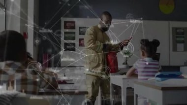 İtfaiyeci sınıfa giriyor. Kırmızı yangın söndürücüyü yerleştiriyor. Eğitimli öğrencilerle toplu iğne çektiğini gösteriyor. Eğitim, güvenlik, eğitim, acil durum, farkındalık, öğretici, toplum