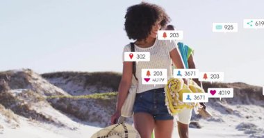 Sosyal medya simgeleri görünüp çoğalırken arkadaşlar havluları taşıyan kum tepecikleri taşıyorlar. Yaz zamanı, açık hava, boş zaman, macera, teknoloji, bağlantı, canlı