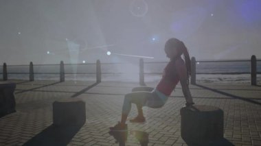 Kadın ellerini bloğun üzerine koyuyor, kavislerle fitness takibi için gezinti güvertesine triseps dalışı yapıyor. Fitness, açık hava egzersizi, gün doğumu, dijital arayüz, atletik, sağlık,