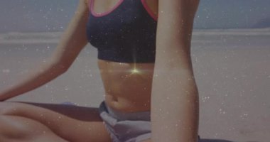 Kamera yoga eğitmenine yakınlaşıyor okyanus kenarındaki mavi mindere meditasyon yapıyor, duruşunu ayarlıyor, sakinliğini buluyor. Zen, sükunet, zindelik, farkındalık, açık hava, dinginlik, sağlık