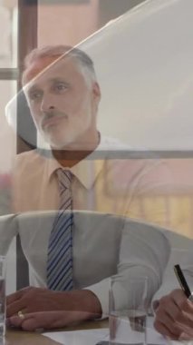 Composite video of close up of wheel of a motorcycle against businesspeople having a meeting. Business technology concept