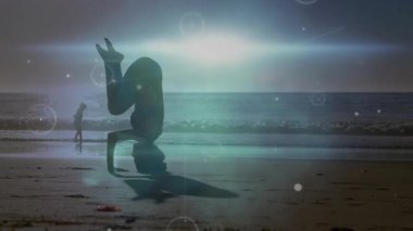 Spor hocası kıyı şeridinde gündoğumunu gerçekleştiriyor, nabız hareketlerini aktive ediyor. Denge, meditasyon, farkındalık, dinginlik, manzara, dijital alarm, sağlık