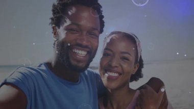 Sahilde kameraya bakan çift, teknolojik açıdan parlayan düğümlere evrimleşiyorlar. Romantik, bağlantı, teknoloji, dijital, fütüristik, dinginlik, rahatlık