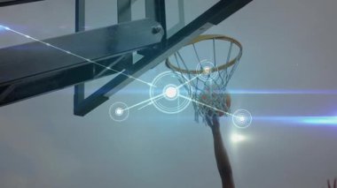 Turuncu basketbol topunu tutarak içeri giren kollar ağların arasından yükseliyor ve düğümler gökyüzüne doğru genişliyor. Atletik, spor, rekabet, açık hava, dijital, fütüristik, dinamik