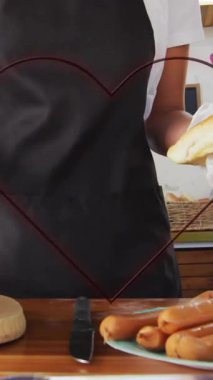 Sosisli hazırlamak, önlüklü, yiyecekten sonra kalp animasyonu yapan insanlar. Yemek pişirme, yemek hazırlama, kalp şekli, animasyon, aşçılık, takım çalışması