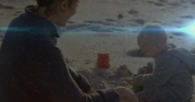 Yeşil kürek kullanan ve kumsalda eğitim için kırmızı kovayı dolduran orta yaşlı bir kadın. Aile, çocukluk, açık hava, rahatlama, neşe, bağ, neşe