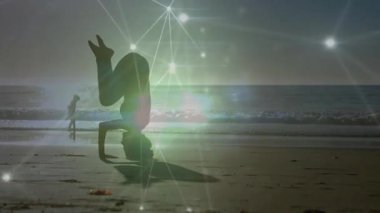 Kafasını kıyı şeridine eğen ve bacaklarını amuda kaldıran bir kadın fitness kaplaması azalıyor. Fitness, yoga, plaj kıyafeti, minimalizm, sağlık, açık hava, dinginlik